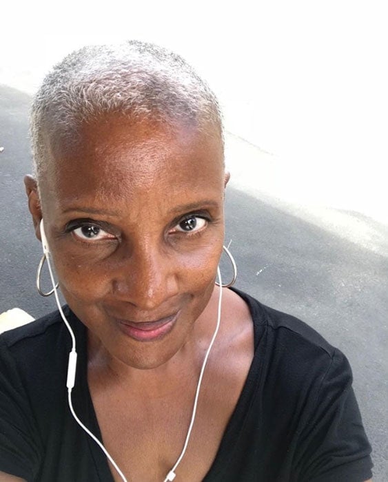 image of black woman with earbuds and buzzed gray hair