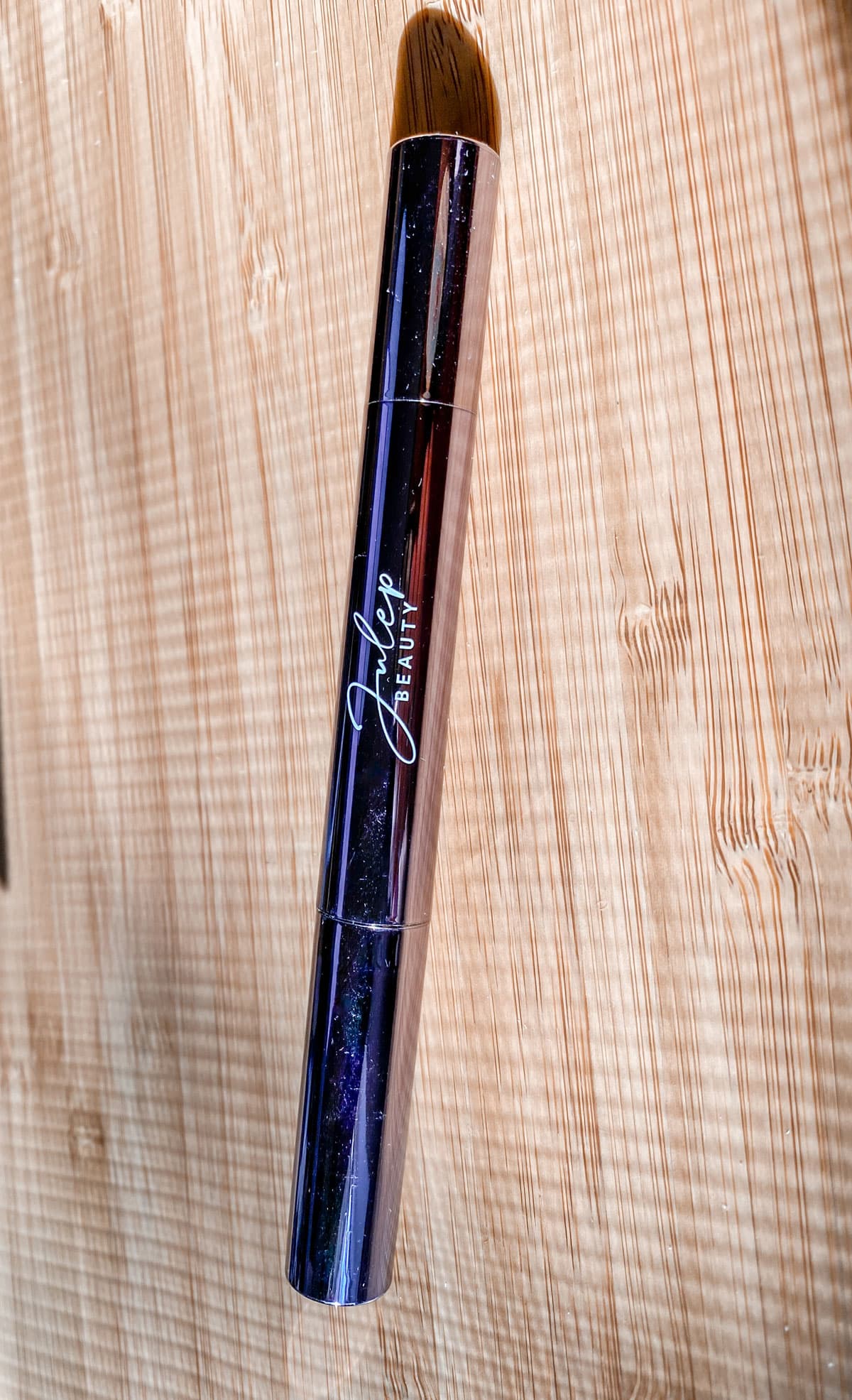 Julep eyeshadow stick (closed) against a wooden background
