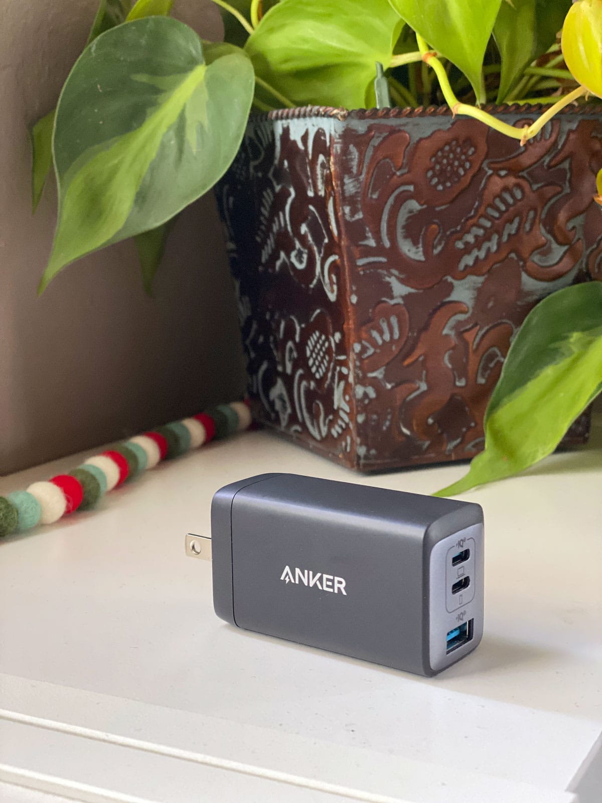 Anker USB-c charger on a white counter near a Christmas garland and a copper planter