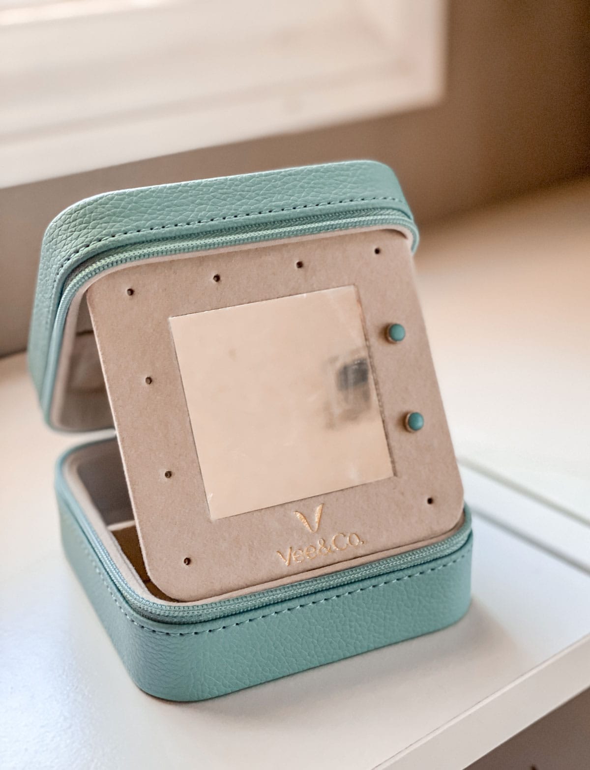 blue small jewelry box, with mirrored part showing, sitting on white countertop