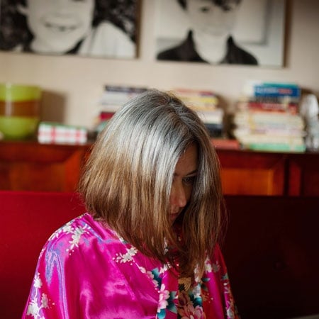 woman with half gray hair and half brassy brunette hair, wearing a pink bathrobe
