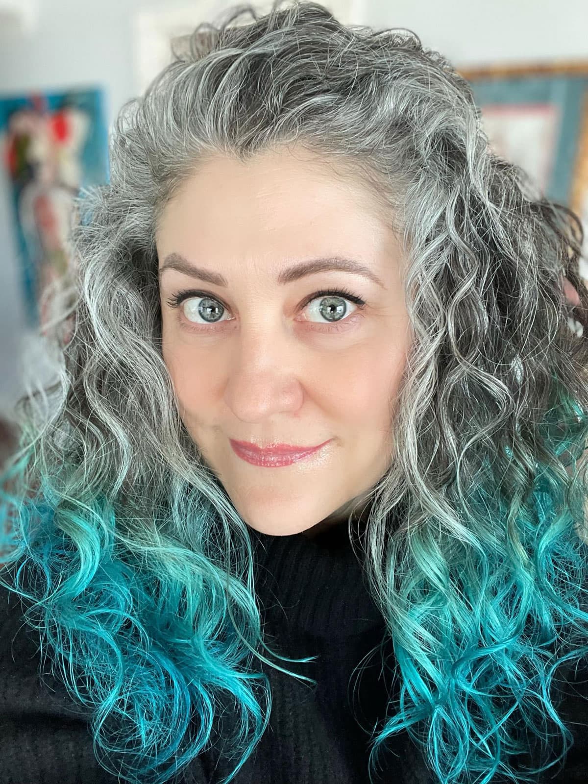 woman with gray curly hair that is colored teal on the ends