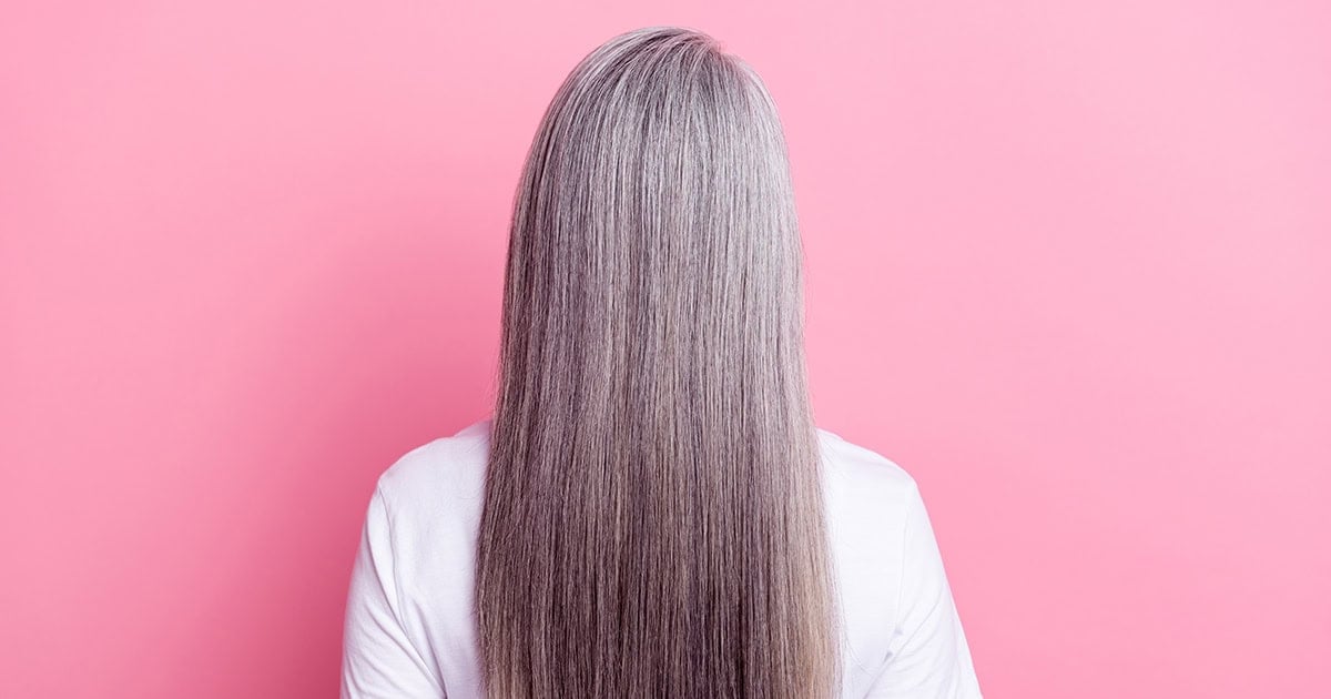 image of straightened gray hair on a woman against a pink background