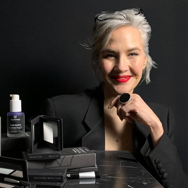 A beautiful gray-haired woman sitting in front of hair products