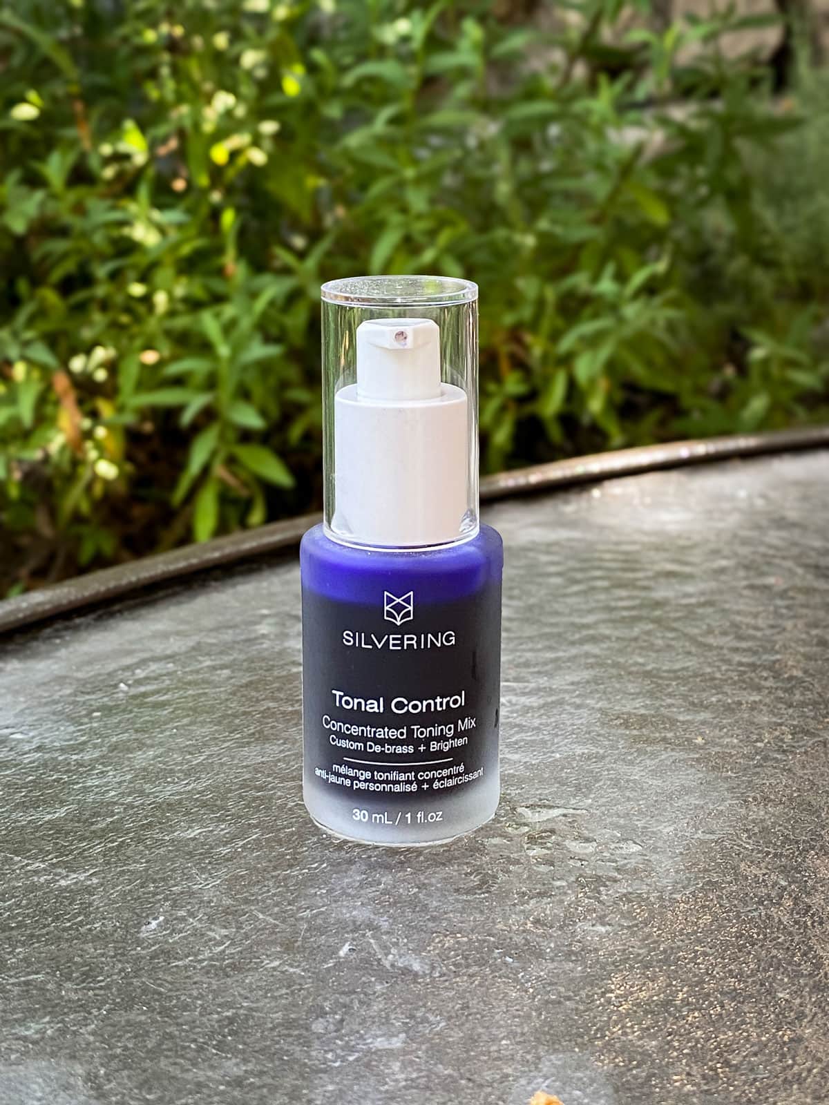 Glass bottled filled with purple liquid (Silvering Tonal Control) sitting on a patio table