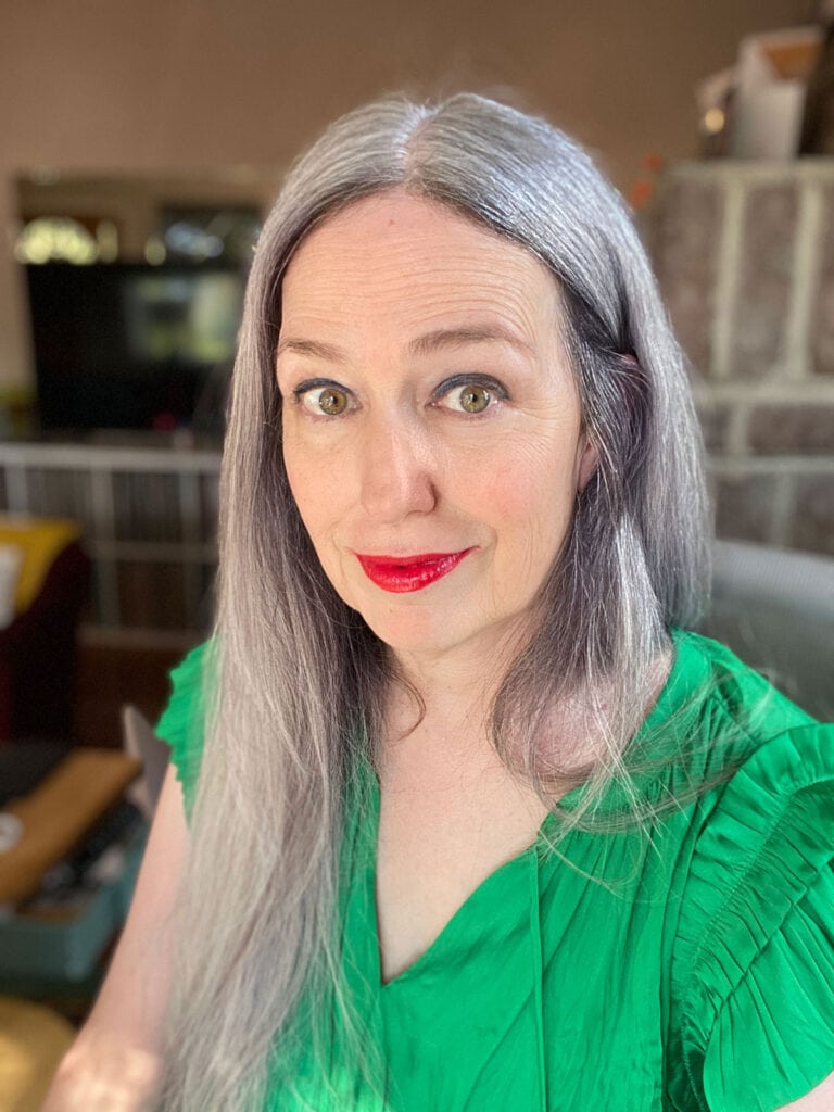 image of woman with long silver hair, red lipstick, and green shirt
