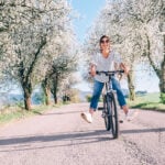 image of midlife woman riding bicycle and laughing