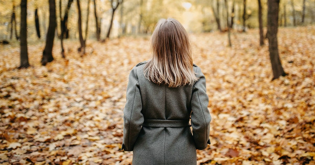 midlife woman walking through Fall forest