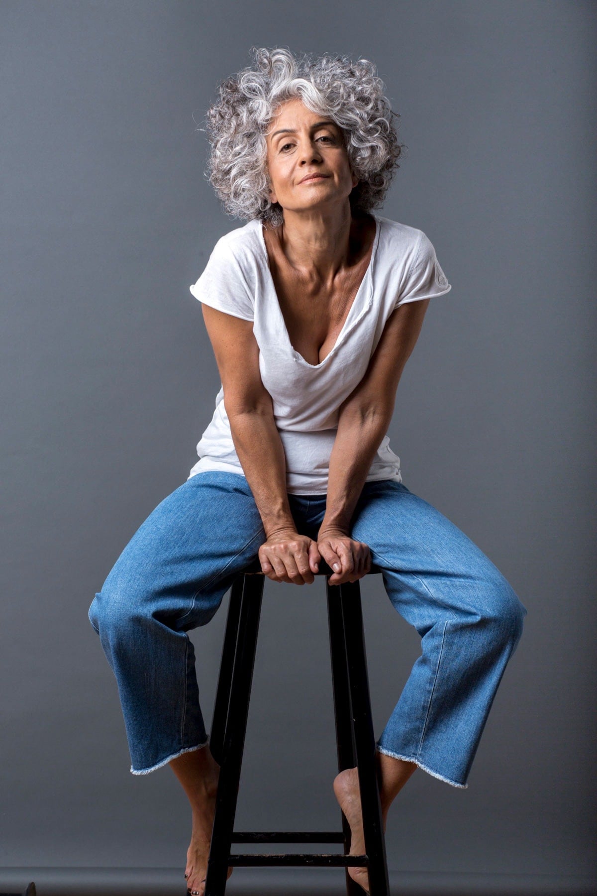 image of Silvina Neder sitting on stool wearing a white tshirt and blue jeans