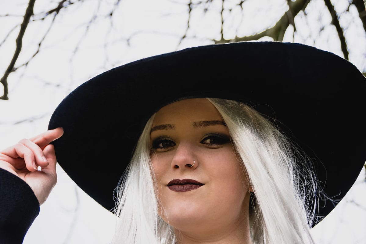 woman with long white hair, dark lipstick and witch hat