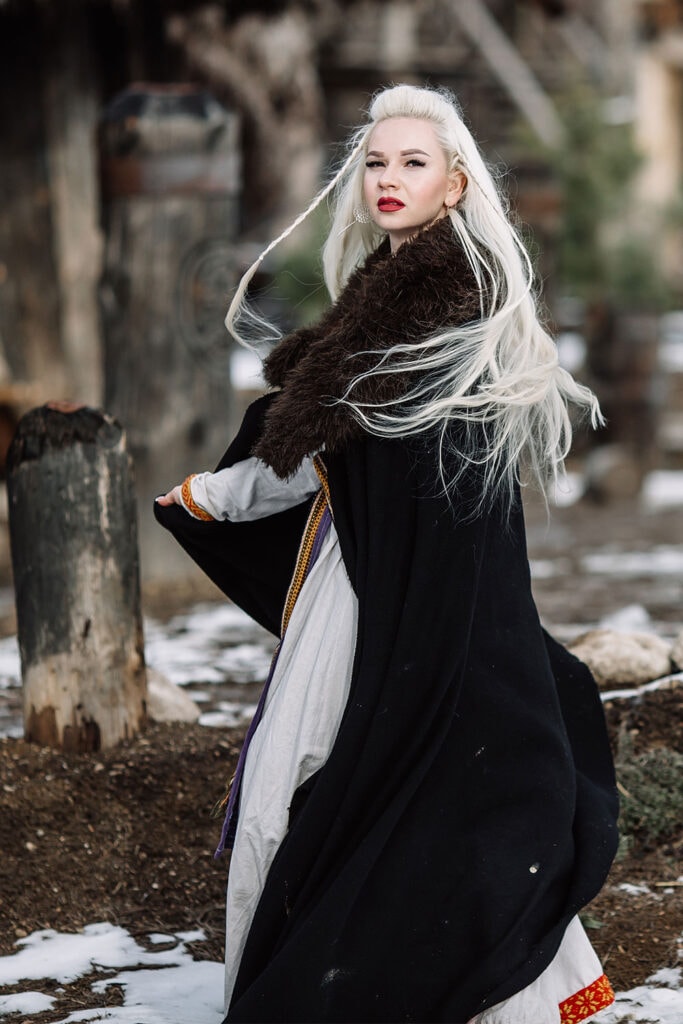 Viking woman wearing dark coat, white dress, and with long white hair