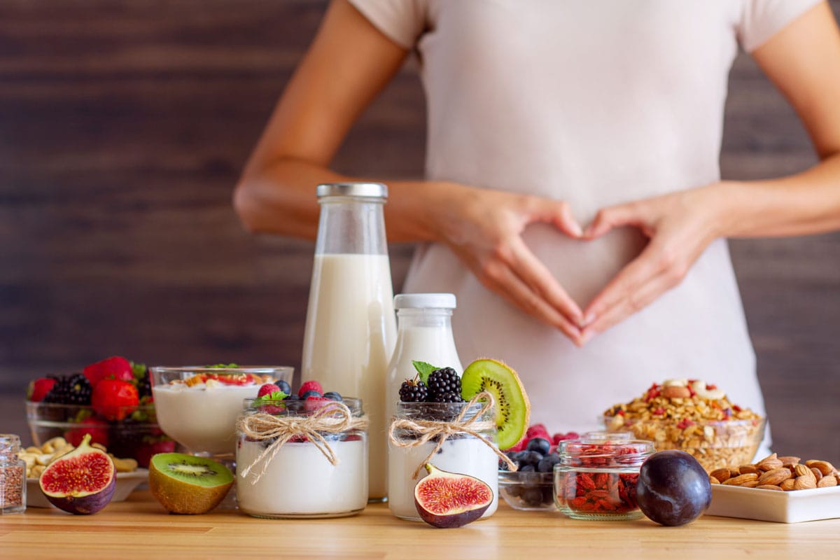 image of gut-friendly foods and a woman holding a heart over her abdomen