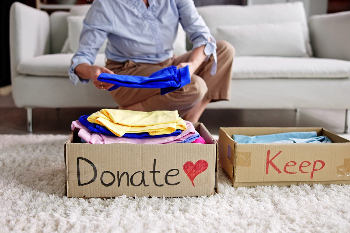 image of woman separating her clothes into two piles: keep and donate