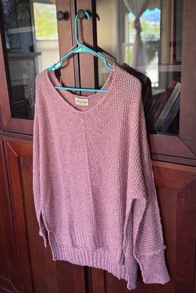 image of a pink knitted sweater hanging on a hanger
