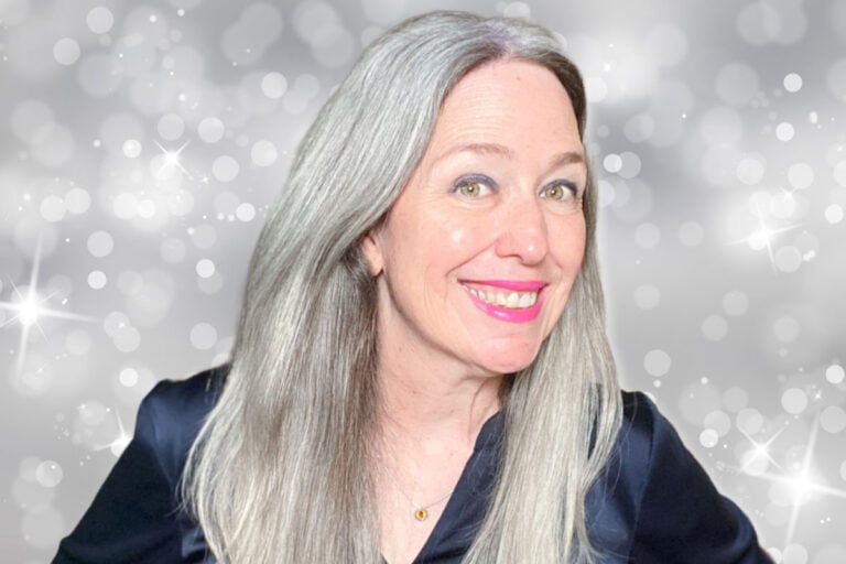 image of woman with bright gray hair against a sparkly background