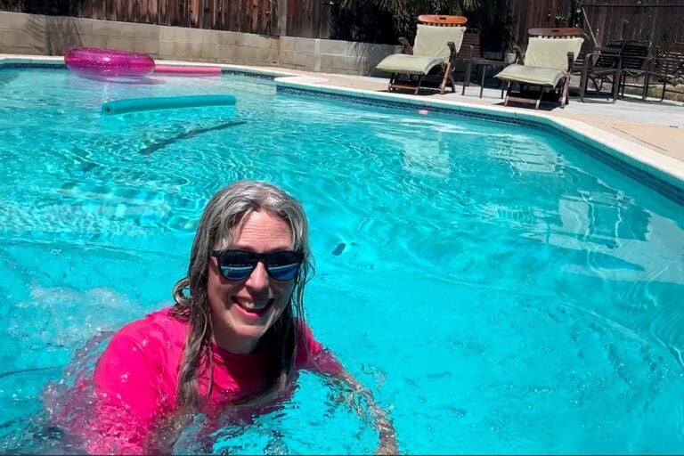 image of woman with gray hair and pink swimshirt swimming in pool