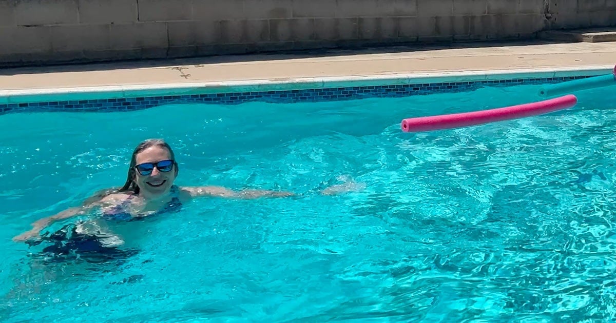 image of gray hair woman swimming and smiling