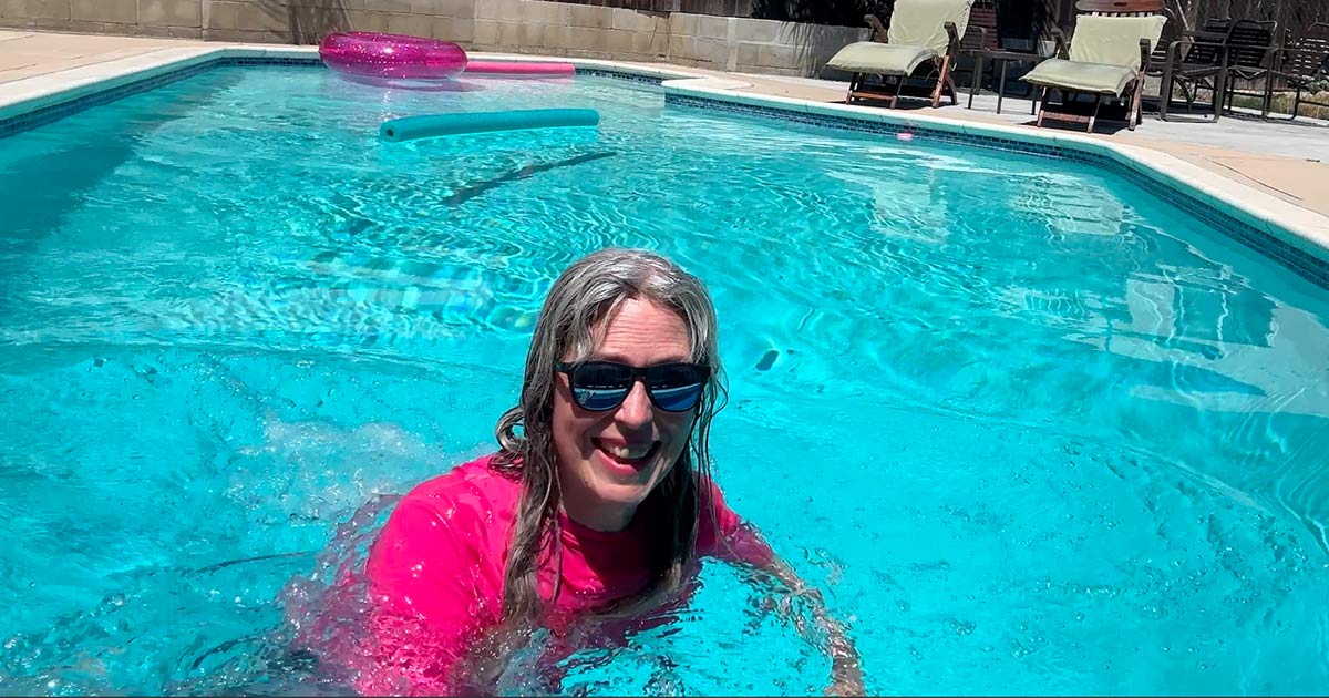 image of woman with gray hair and pink swimshirt swimming in pool