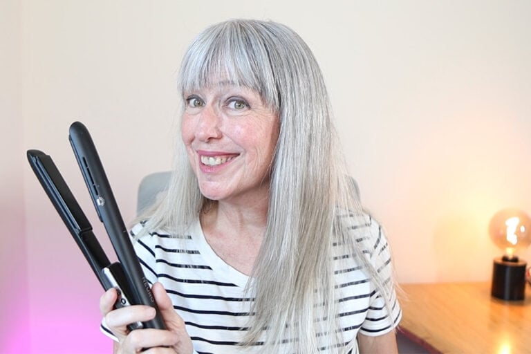 image of Katie with sleek hair smiling and holding paul mitchell neuro flat iron